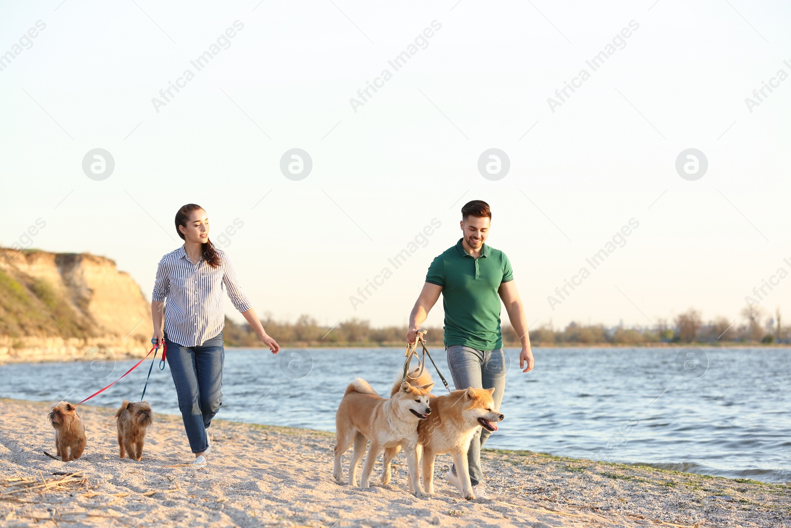 Photo of Young couple walking their adorable dogs near river