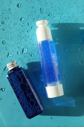 Photo of Bottles of cosmetic products on wet turquoise background, top view