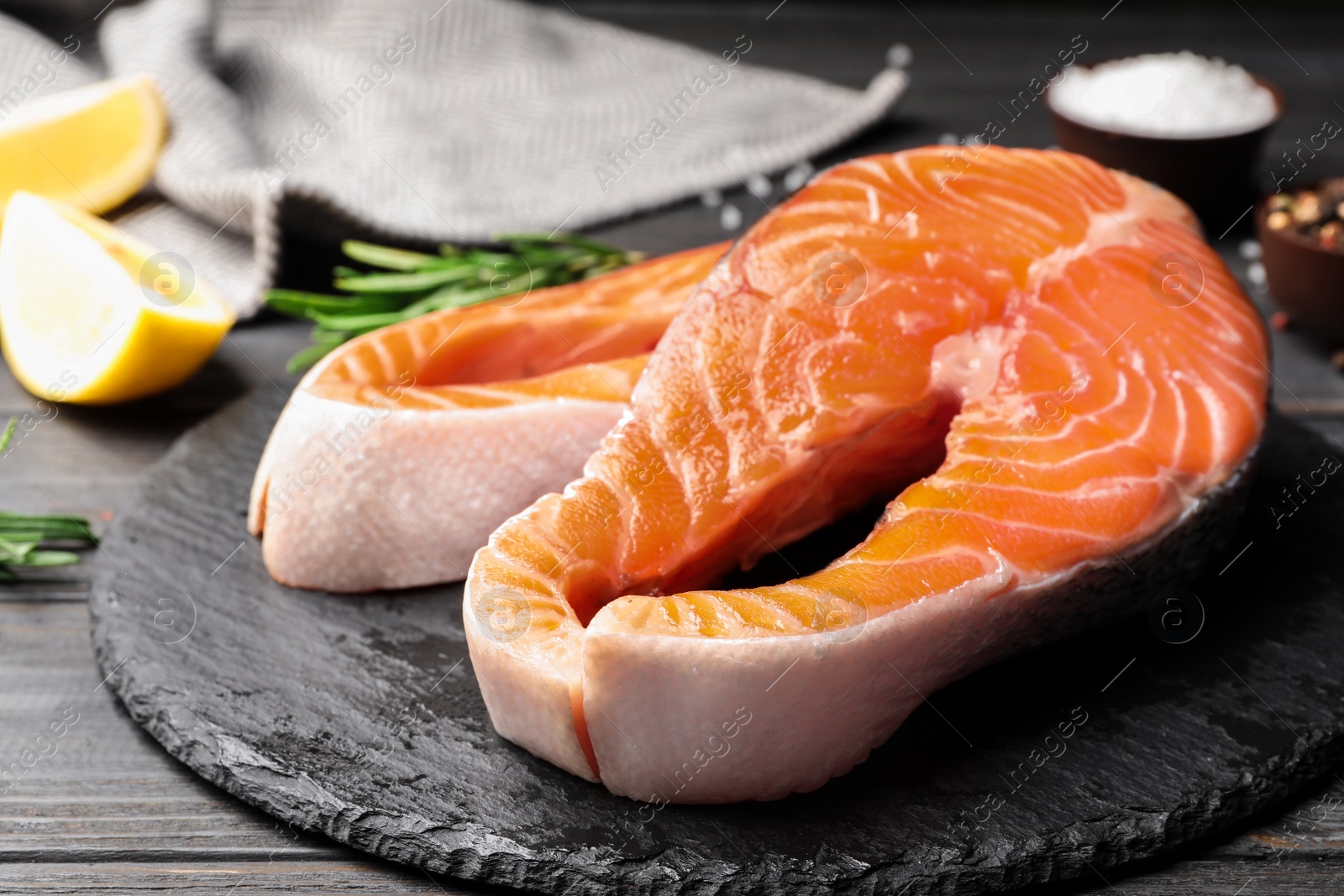 Photo of Fresh salmon steaks on black wooden table