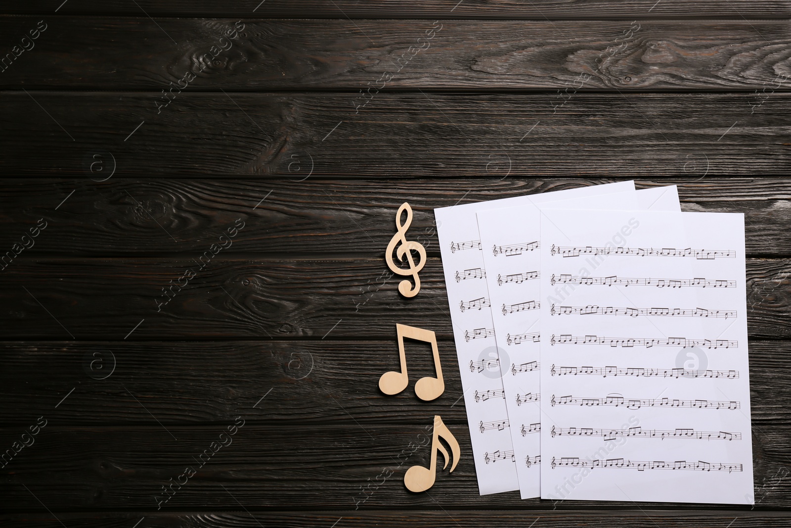 Photo of Sheets and music notes on wooden background, top view. Space for text