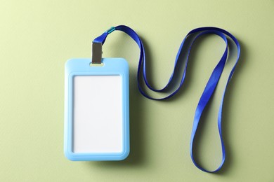 Photo of Blank light blue badge with string on green background, top view