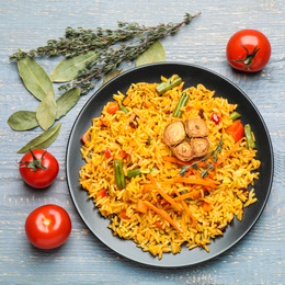 Photo of Tasty rice pilaf with vegetables on grey wooden table, flat lay