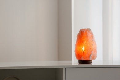 Photo of Exotic Himalayan salt lamp on cabinet indoors