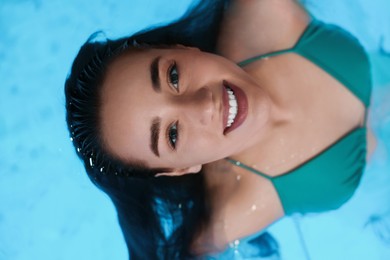 Photo of Beautiful woman relaxing in spa swimming pool, top view