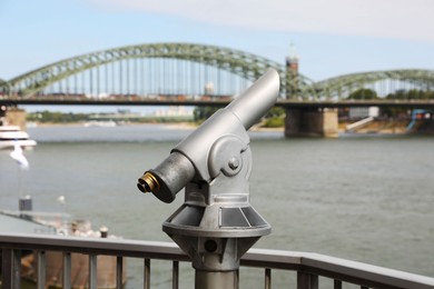 Modern public telescope near river on sunny day