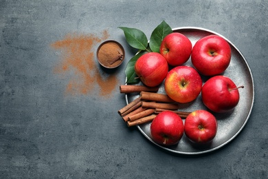 Photo of Fresh apples with cinnamon sticks and powder on gray table, top view