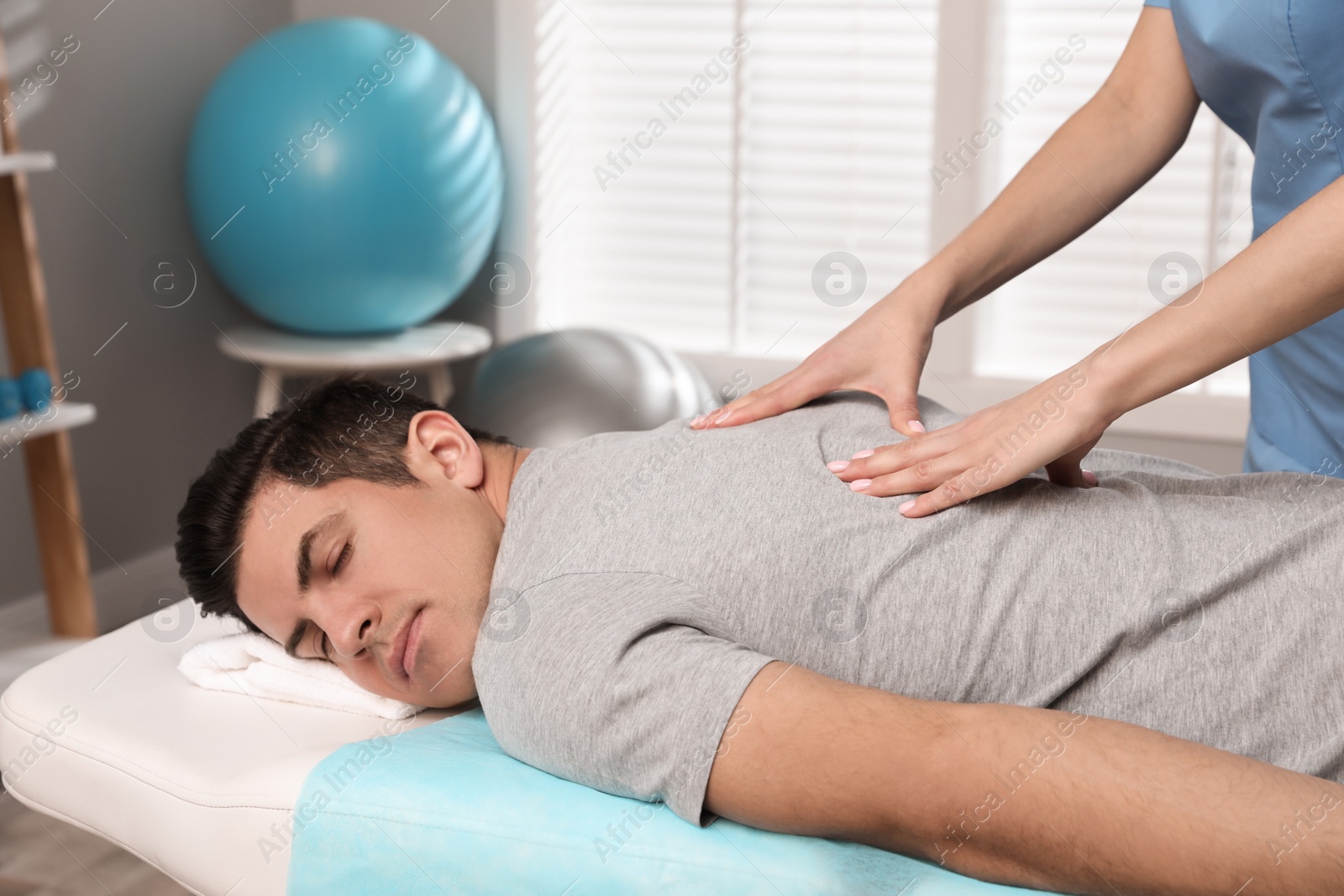 Photo of Orthopedist massaging man's back in clinic, closeup. Scoliosis treatment