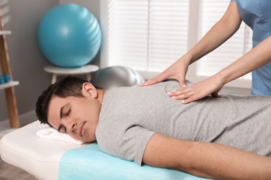 Photo of Orthopedist massaging man's back in clinic, closeup. Scoliosis treatment