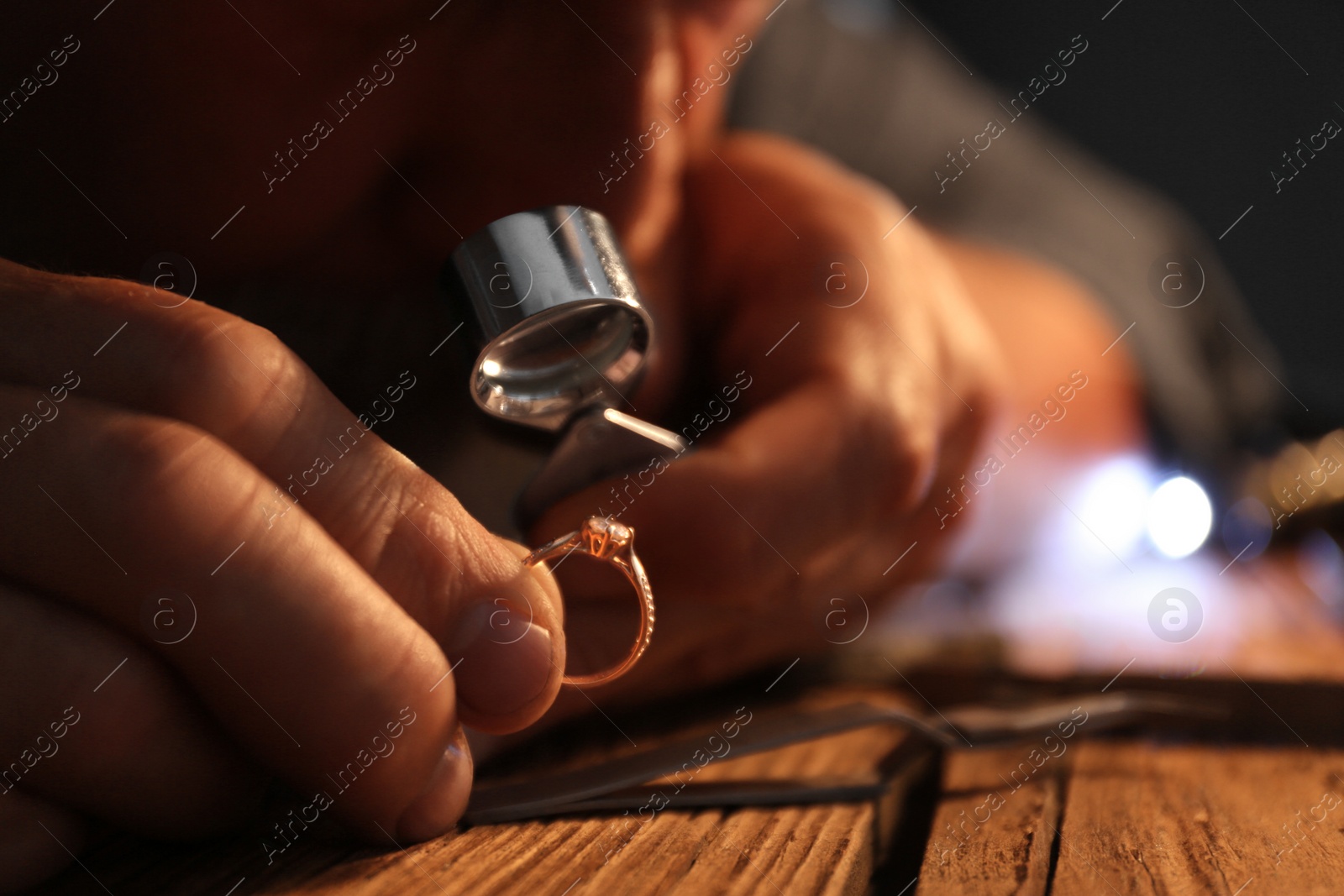 Photo of Male jeweler evaluating diamond ring in workshop, closeup view