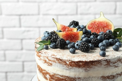 Delicious homemade cake with fresh berries near brick wall, closeup