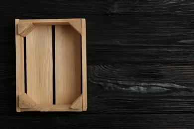 Photo of Empty wooden crate on dark background, top view with space for text