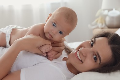 Happy young mother with her cute baby on bed at home