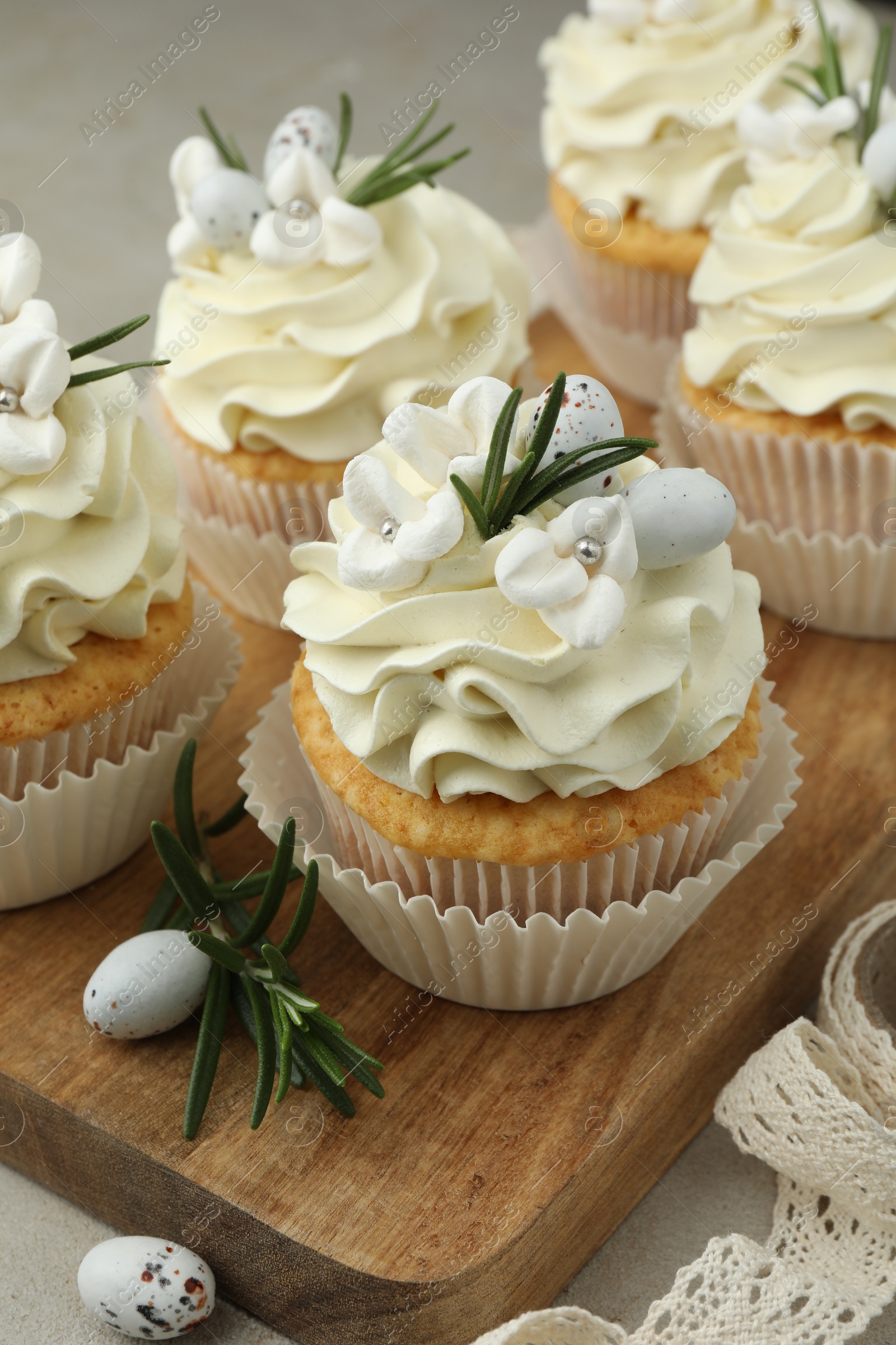 Photo of Tasty Easter cupcakes with vanilla cream on table, closeup