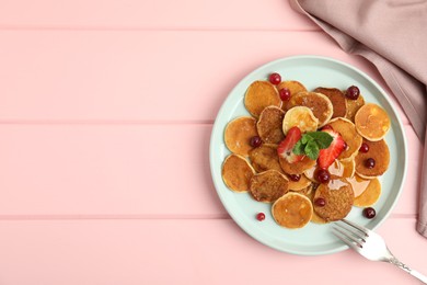 Photo of Cereal pancakes with berries on pink wooden table, flat lay. Space for text