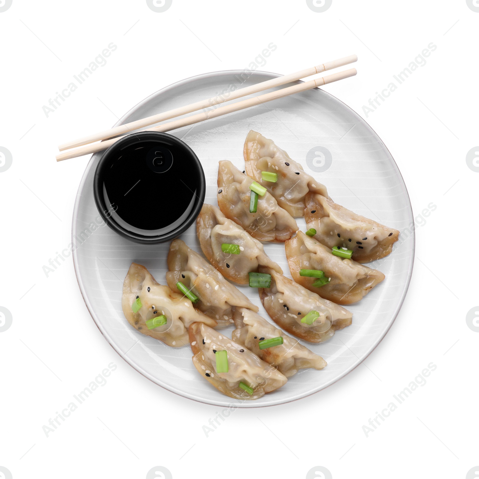 Photo of Delicious gyoza (asian dumplings) with green onions, soy sauce and chopsticks isolated on white, top view