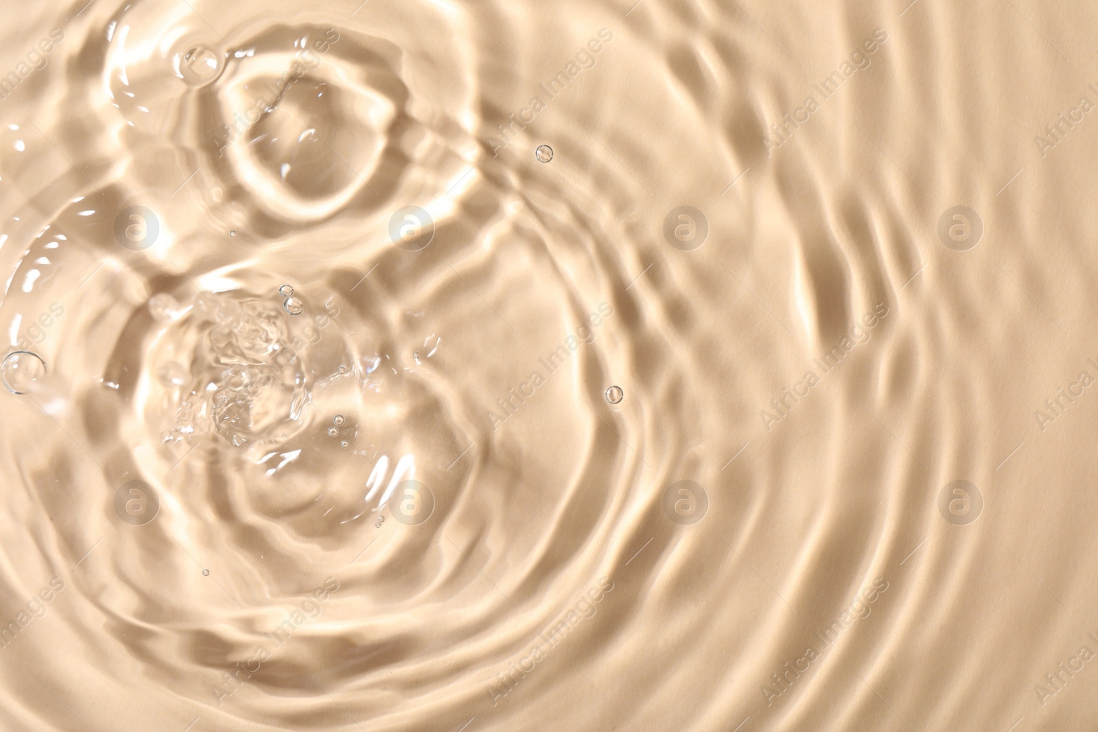 Photo of Closeup view of water with rippled surface on beige background