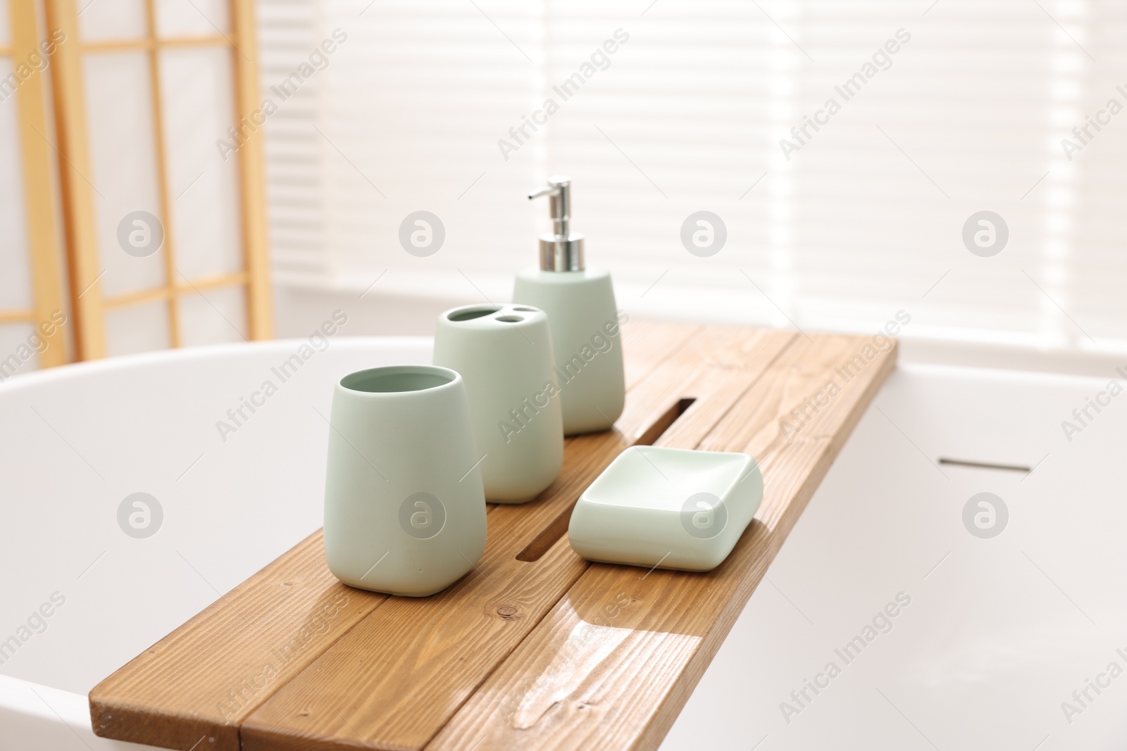 Photo of Set of bath accessories on tub in bathroom