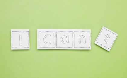 Photo of Motivation concept. Changing phrase from I Can't into I Can by removing paper with letter T on light green background, flat lay