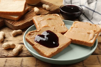 Photo of Tasty peanut butter sandwiches with jam on wooden table, closeup