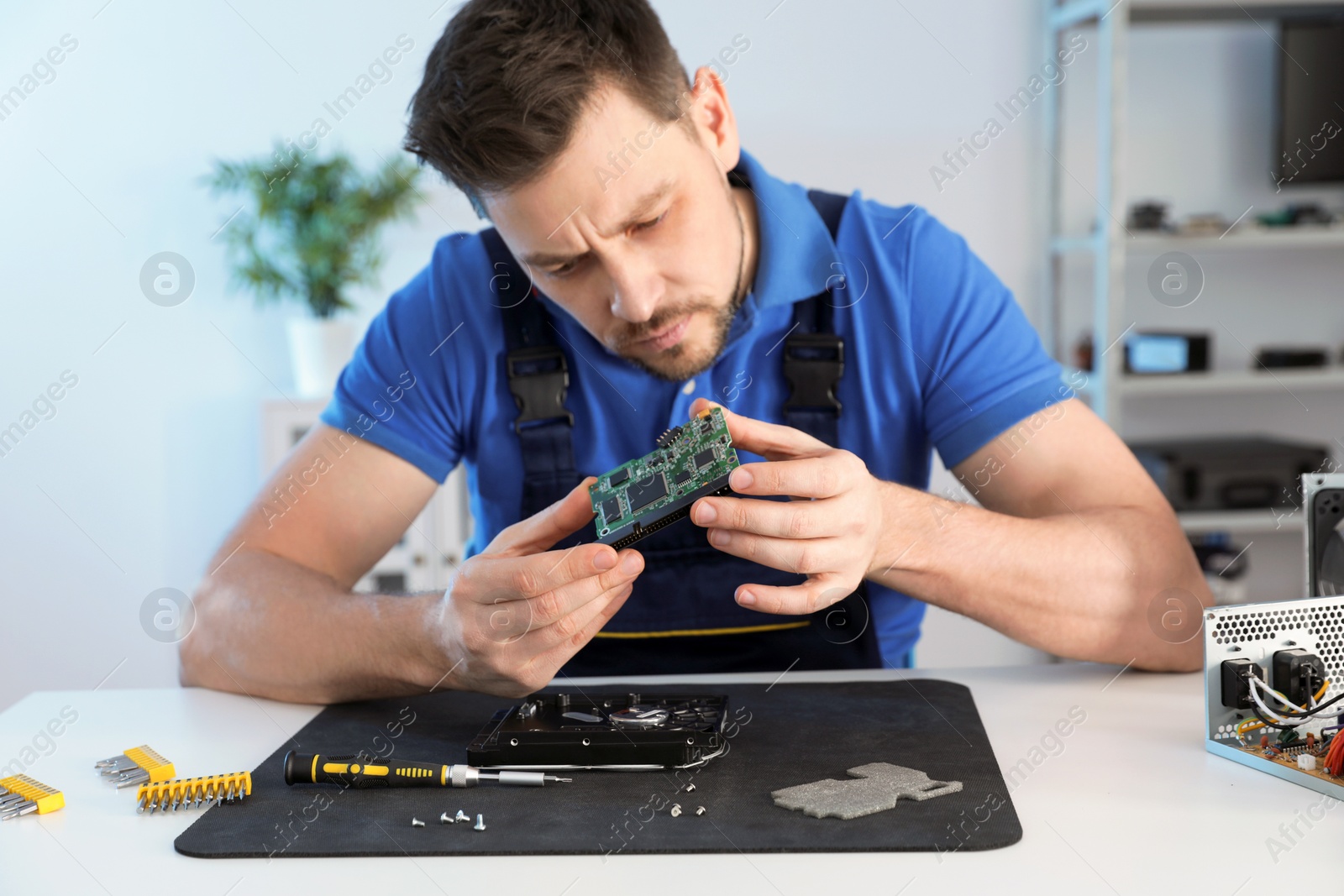 Photo of Male technician repairing hard drive at table indoors