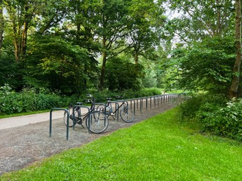 Photo of Parked bicycles near metal stands in green park