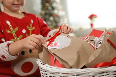 Photo of Cute little girl taking gift from Christmas advent calendar at home, closeup