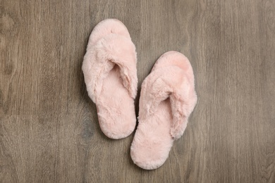 Photo of Pair of soft slippers on wooden background, flat lay