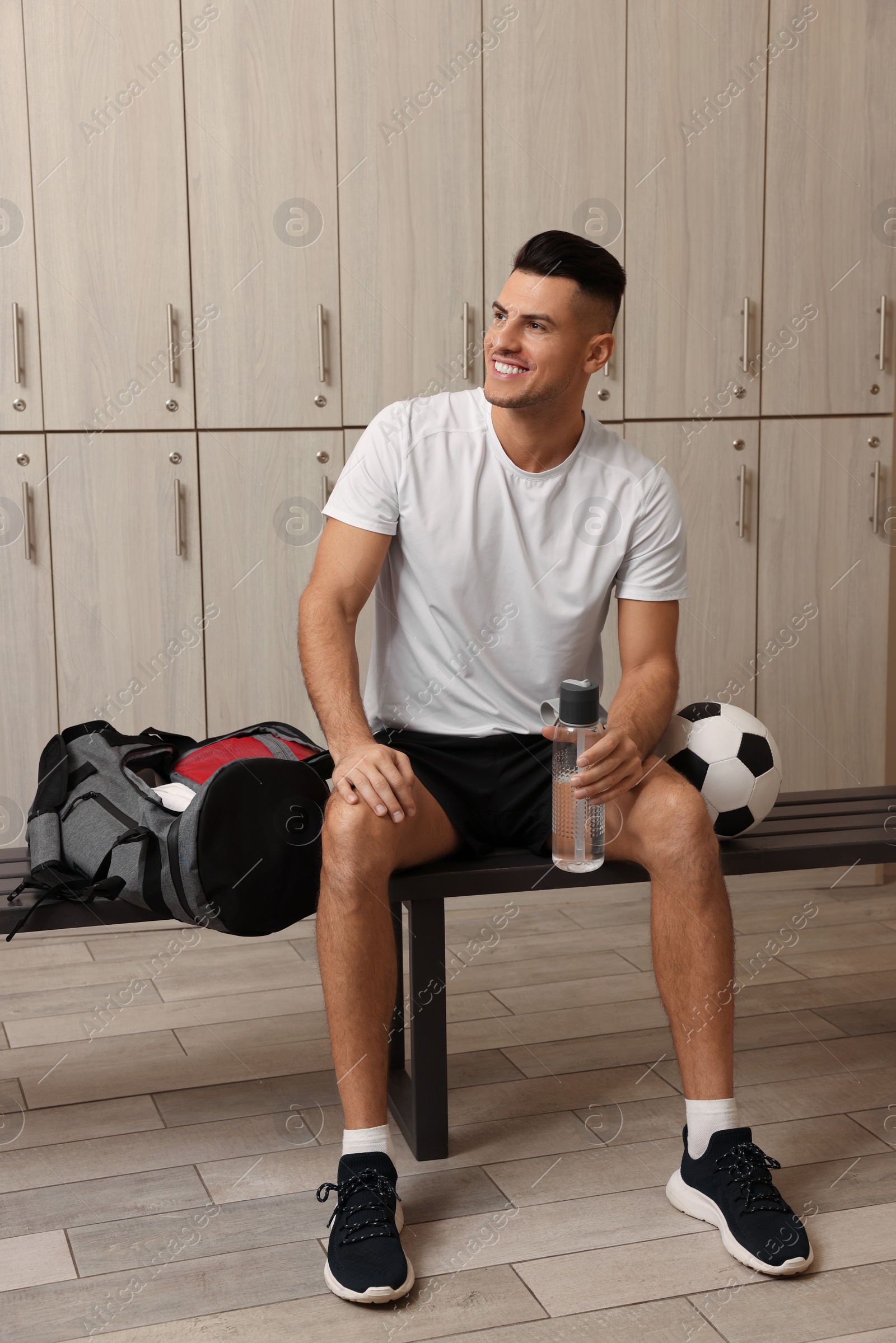 Photo of Handsome man with bottle of water in locker room