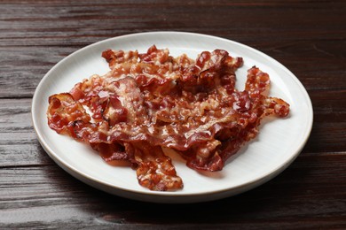 Slices of tasty fried bacon on wooden table