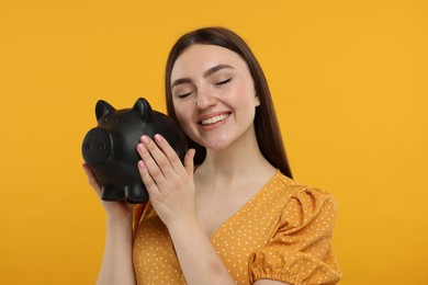 Photo of Happy woman with piggy bank on orange background