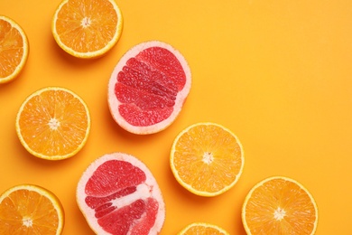 Photo of Cut citrus fruits on orange background, flat lay. Space for text