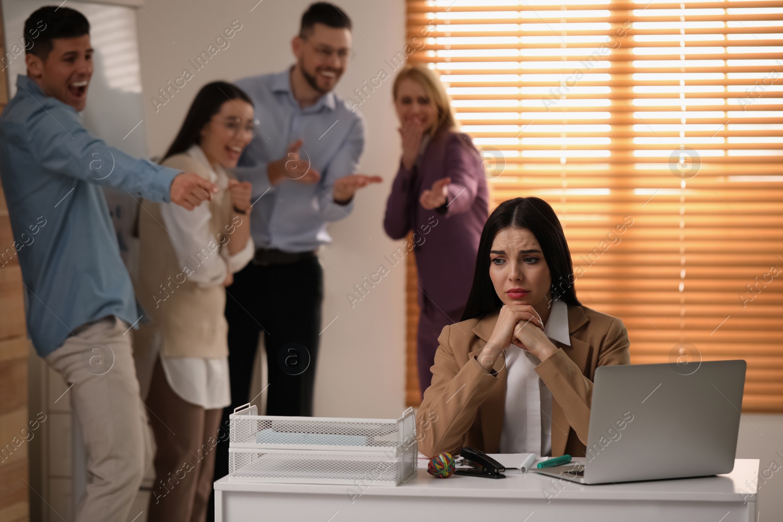 Photo of Coworkers bullying their colleague at workplace in office