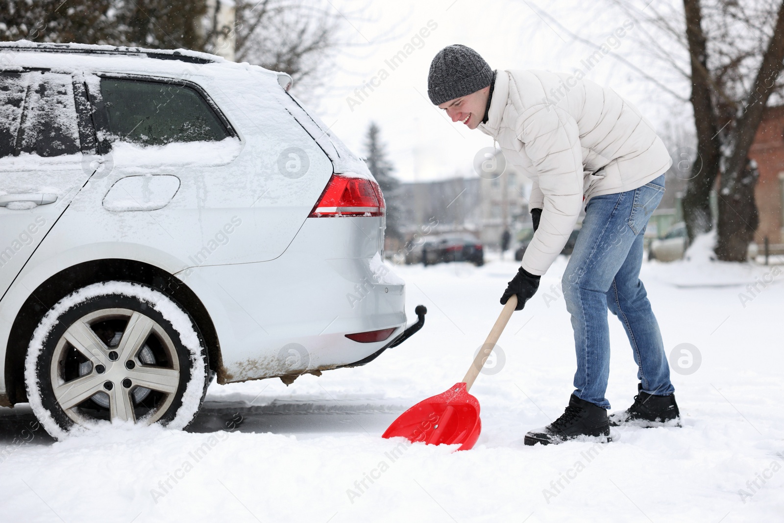 Photo of Man removing snow with shovel near car outdoors