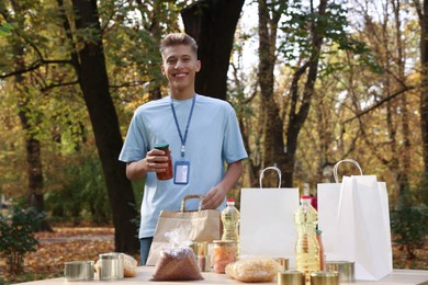 Portrait of volunteer packing food products at table in park