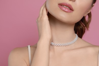 Photo of Young woman wearing elegant pearl necklace on pink background, closeup