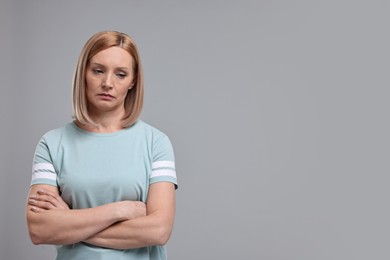Photo of Portrait of sad woman with crossed arms on grey background. Space for text