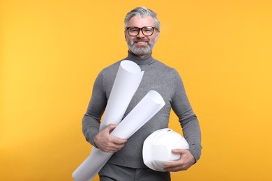 Photo of Architect with hard hat and drafts on orange background