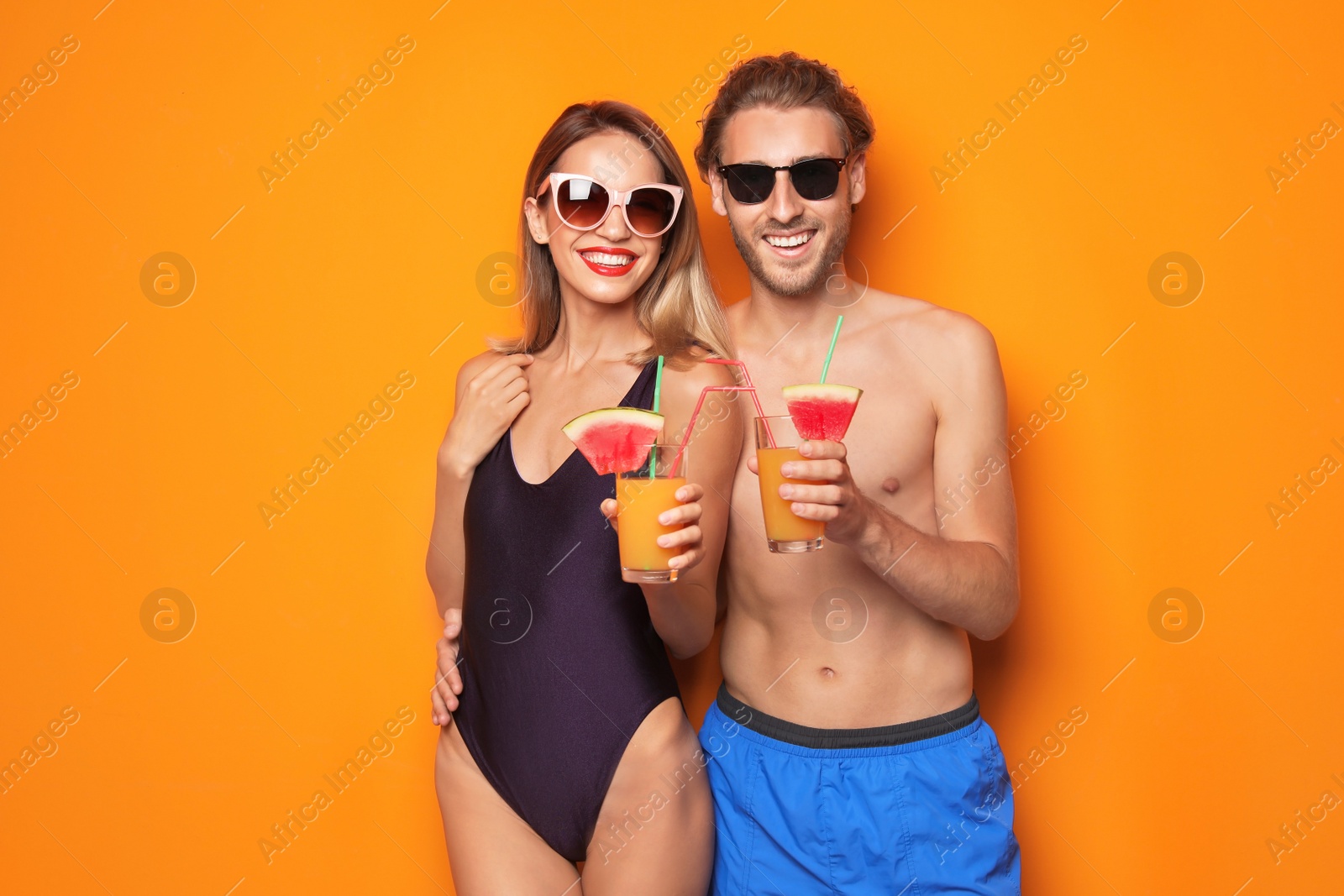 Photo of Happy young couple in beachwear with cocktails on color background