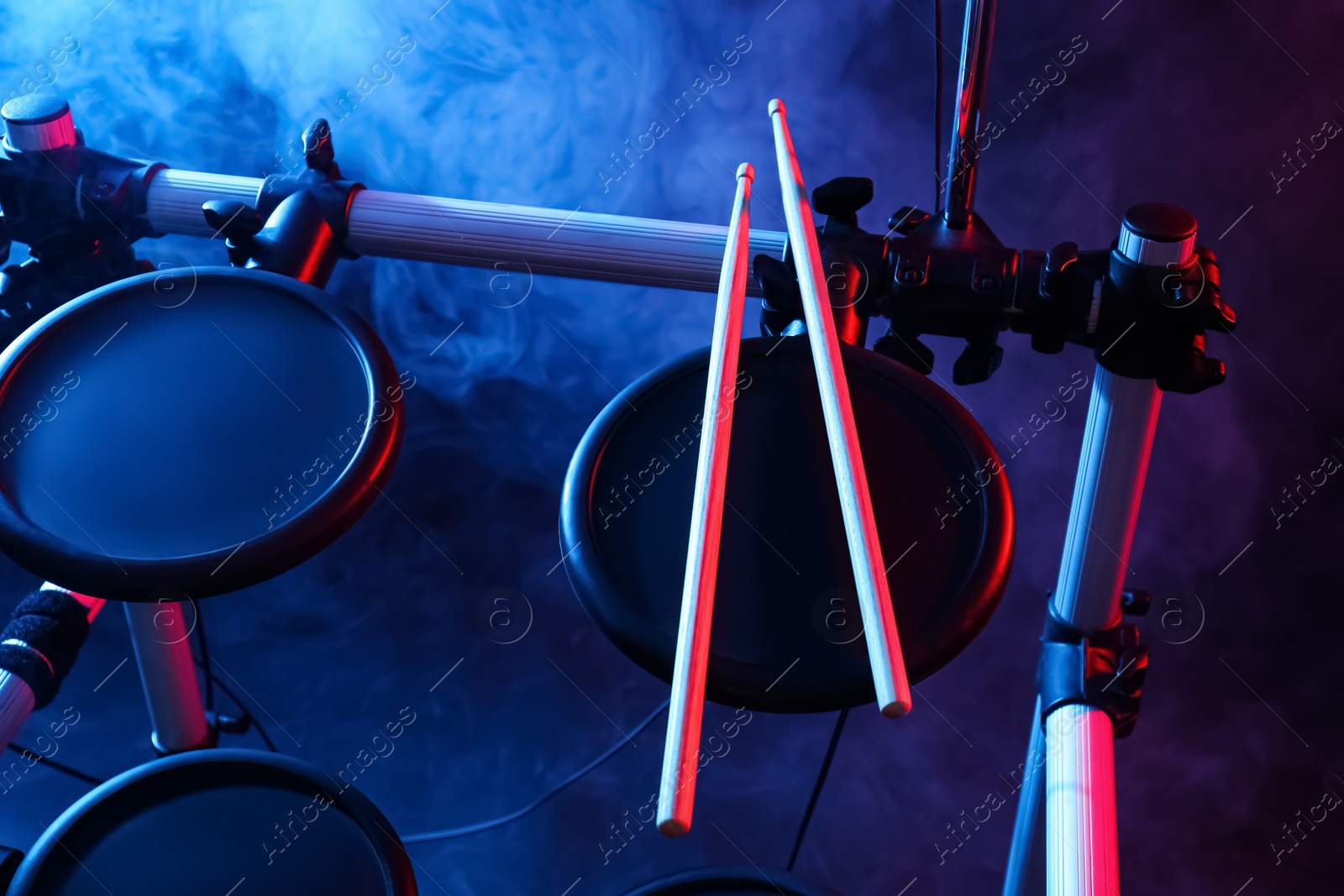 Photo of Modern electronic drum kit with sticks on dark background, color toned. Musical instrument