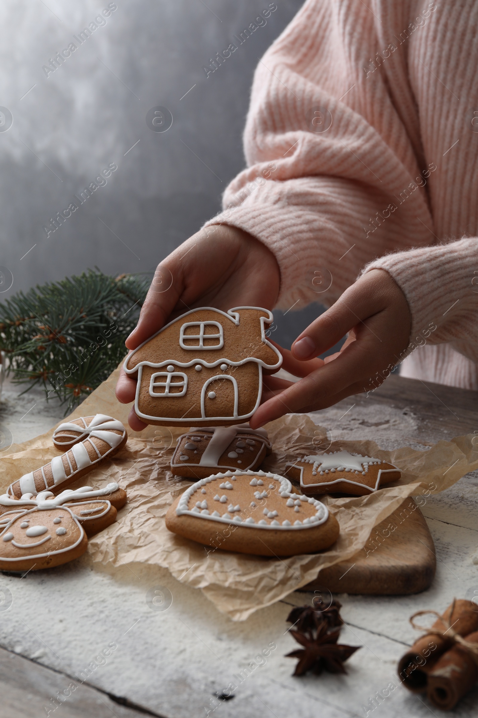 Photo of Woman holding delicious homemade Christmas cookie at wooden table, closeup