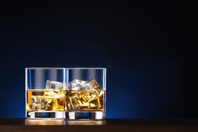 Photo of Whiskey with ice cubes in glasses on table. Space for text