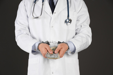 Photo of Doctor in handcuffs with bribe on black background, closeup. Corrupted medicine