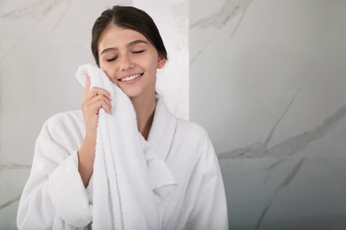 Beautiful teenage girl wiping face with towel at home, space for text