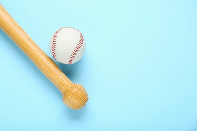 Photo of Wooden baseball bat and ball on light blue background, flat lay. Space for text