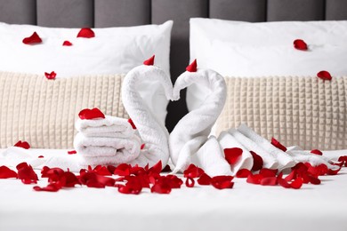 Photo of Honeymoon. Swans made with towels and beautiful rose petals on bed