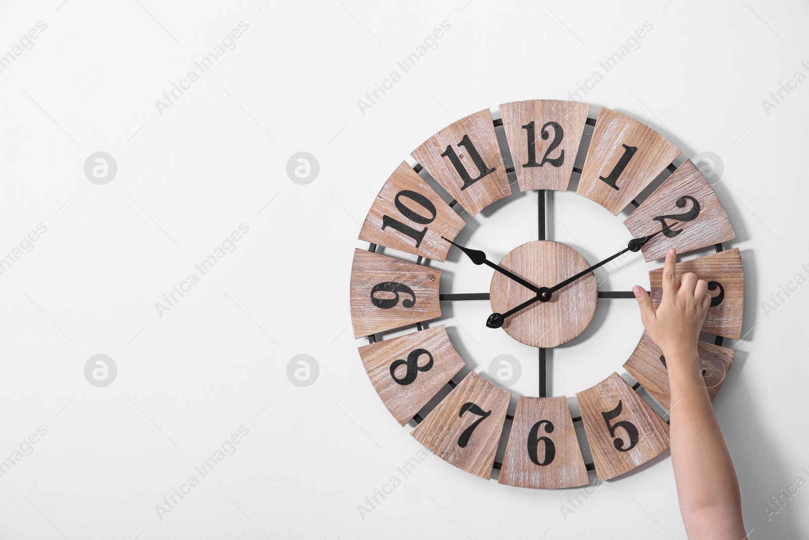 Photo of Woman adjusting clock on white wall, space for text. Time change
