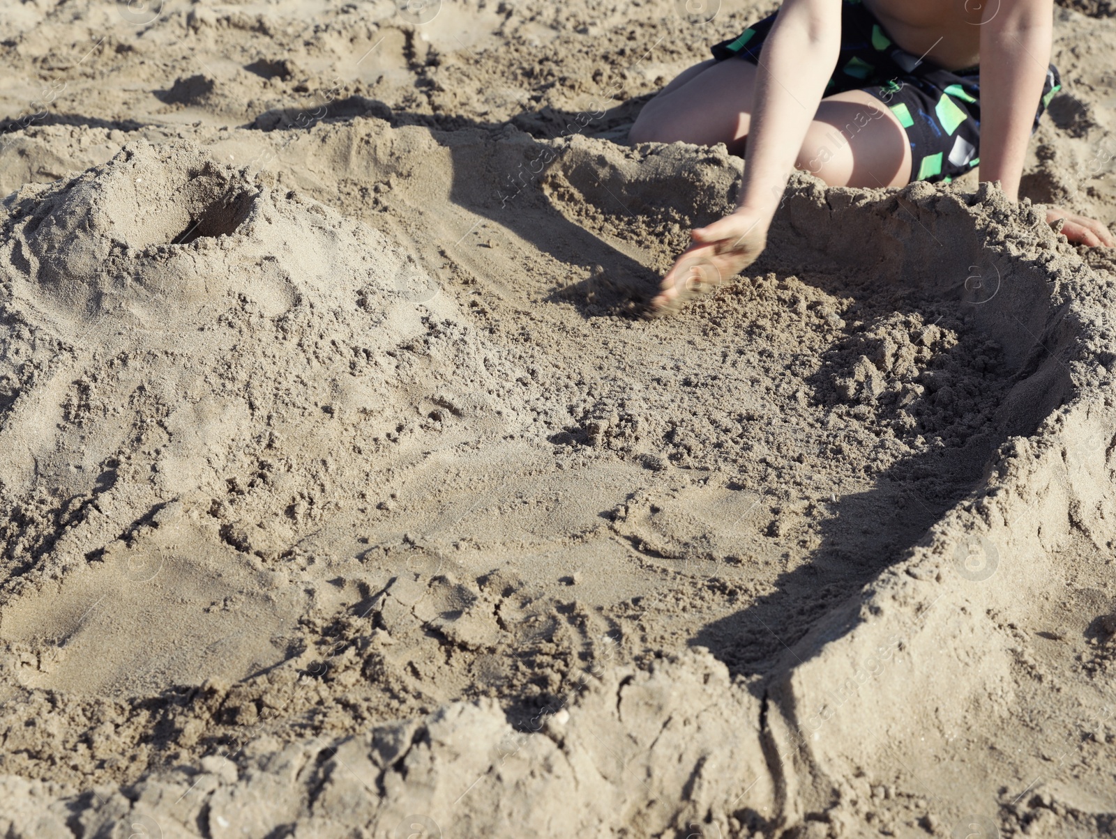 Photo of Little boy playing with sand on sunny day, closeup