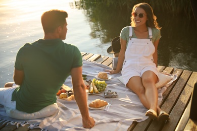 Photo of Happy couple spending time on pier at picnic