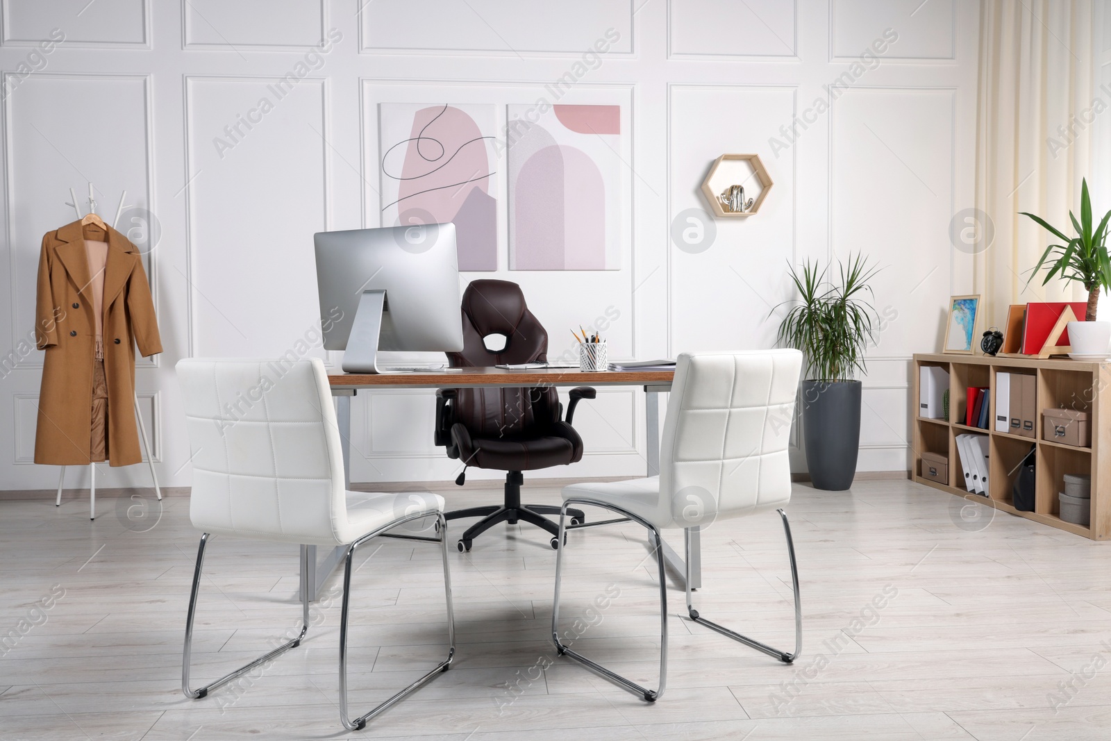 Photo of Director's workplace with wooden table, computer and comfortable armchairs. Interior design