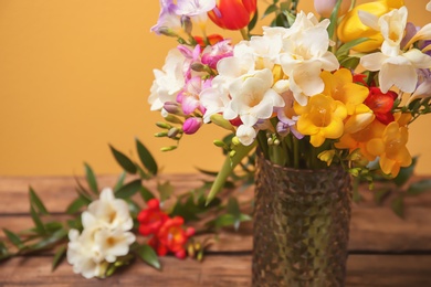 Vase with beautiful freesia flowers on table